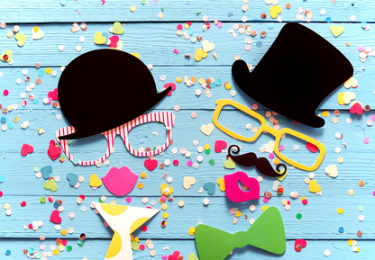 Partying with photo booth people composed of colorful accessories with a gent and lady in top hats and sunglasses sipping holiday cocktails surrounded by confetti on a blue wood background